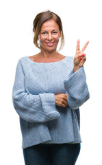 Poster - Middle age senior hispanic woman wearing winter sweater over isolated background smiling with happy face winking at the camera doing victory sign. Number two.