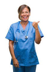 Poster - Middle age senior nurse doctor woman over isolated background smiling with happy face looking and pointing to the side with thumb up.