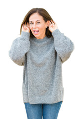 Canvas Print - Beautiful middle age woman wearing winter sweater over isolated background Trying to hear both hands on ear gesture, curious for gossip. Hearing problem, deaf