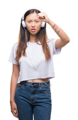 Canvas Print - Young asian woman listening to music wearing headphones isolated background annoyed and frustrated shouting with anger, crazy and yelling with raised hand, anger concept