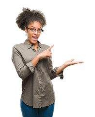 Poster - Young afro american woman wearing glasses over isolated background amazed and smiling to the camera while presenting with hand and pointing with finger.