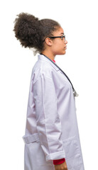 Wall Mural - Young afro american doctor woman over isolated background looking to side, relax profile pose with natural face with confident smile.