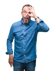 Poster - Middle age hoary senior man wearing glasses over isolated background doing ok gesture shocked with surprised face, eye looking through fingers. Unbelieving expression.