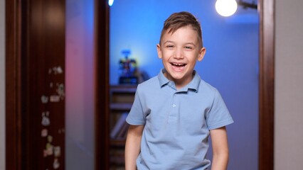 Boy wearing a blue shirt is laughing in a room