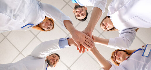 Canvas Print - Team of doctors putting hands together, bottom view