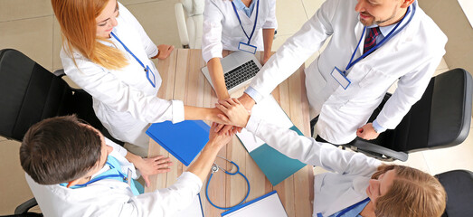 Canvas Print - Team of doctors putting hands together, top view