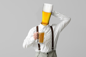 Sticker - Young man in traditional German clothes with beer on light background