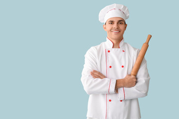 Poster - Handsome happy male chef with rolling pin on blue background