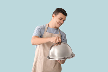 Canvas Print - Handsome happy male chef with tray and cloche on blue background