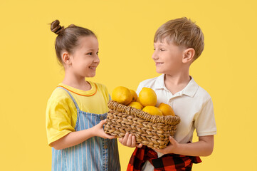 Poster - Cute children with basket of lemons on yellow background