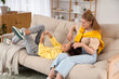 © Pixel-Shot - Young women using mobile phone on sofa at home