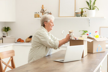 Wall Mural - Senior woman with boxes of garbage in kitchen. Waste sorting concept