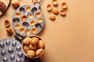 Wall Mural - Bowl with tasty walnut shaped cookies and baking form on color background