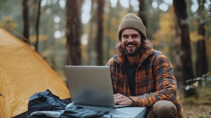 Poster - A man with a beaming smile works on his laptop, enjoying the tranquility of wooded surroundings and vibrant fall foliage