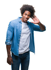 Poster - Afro american man over isolated background smiling with hand over ear listening an hearing to rumor or gossip. Deafness concept.