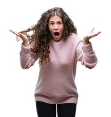 Wall Mural - Beautiful brunette curly hair young girl wearing pink winter sweater over isolated background celebrating crazy and amazed for success with arms raised and open eyes screaming excited. Winner concept