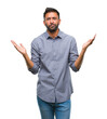 © Krakenimages.com - Adult hispanic man over isolated background clueless and confused expression with arms and hands raised. Doubt concept.