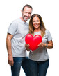 © Krakenimages.com - Middle age hispanic casual couple in love holding red heart over isolated background with a happy face standing and smiling with a confident smile showing teeth