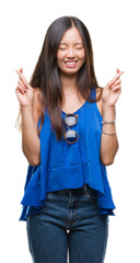 Wall Mural - Young asian woman over isolated background smiling crossing fingers with hope and eyes closed. Luck and superstitious concept.