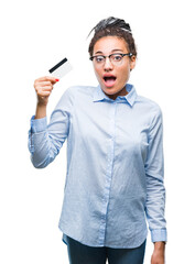 Wall Mural - Young african american girl holding credit card over isolated background scared in shock with a surprise face, afraid and excited with fear expression