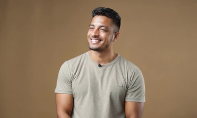 Canvas Print - Portrait of a happy young indian man smiling against brown background