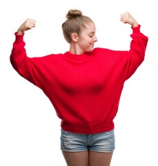 Wall Mural - Young blonde woman wearing bun and red sweater showing arms muscles smiling proud. Fitness concept.