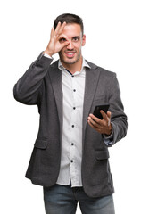 Canvas Print - Handsome young man using smartphone with happy face smiling doing ok sign with hand on eye looking through fingers