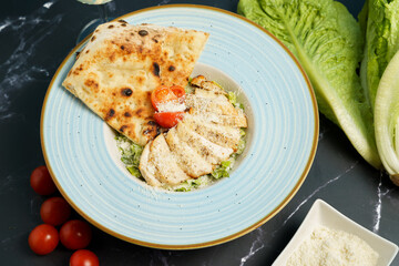 Caesar salad with fried chicken slices, tomato, parmesan cheese, tomato and crispy focaccia