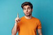 © MUdaylah - Photo of attractive dreamy man dressed orange shirt looking showing finger empty space isolated blue color background with generative ai
