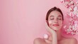 © anatoliycherkas - Beautiful Woman Enjoying Skincare Routine with Cream and Blossoms on Pink Background