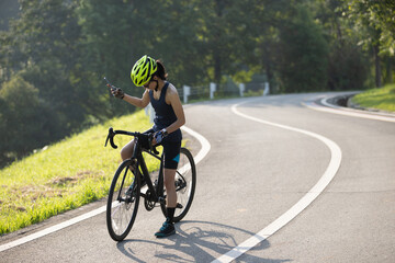 Wall Mural - Woman cyclist using mobile phone at summer park