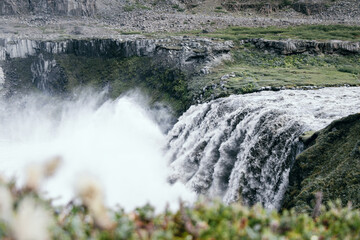 Hafragilsfoss in barren lanscape with only few green plants and dirty water