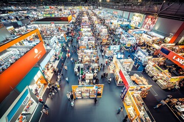 Wall Mural - Numerous exhibitors present their offerings to a large crowd at a vibrant trade fair, creating an atmosphere of excitement and opportunity