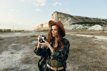 Wall Mural - desert wanderlust woman in widebrim hat capturing the beauty of arid landscape with vintage camera