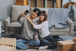 © ARMMY PICCA - Young Asian couple relocating to a new house, joyfully packing and unpacking belongings. Expertise in moving, packing, togetherness, and creating a new home together.
