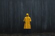 © TEERAPAT - A person in a yellow raincoat stands in front of a wall