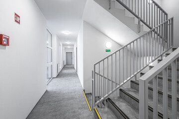 modern hallway with stairs and metal railings in a bright building, featuring geometric lines and a 