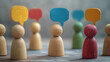 © Taskmanager - Wooden figures with colored speech bubbles above their heads stand on a textured background. The image represents communication, ideas, and diversity in dialogue.