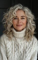 Wall Mural - A woman with long blonde hair is wearing a white sweater and smiling. The sweater is knitted and has a pattern of white and black