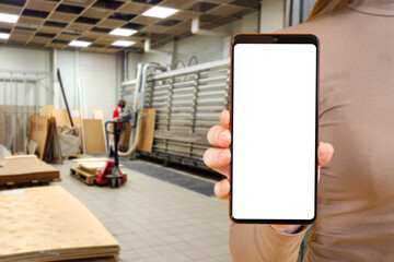 Poster - Woman with phone stands in workshop. Cellphone with white screen. Cropped lady inside industrial space. Smartphone template for commercial proposal. Workshop ads. Mobile phone with blank display