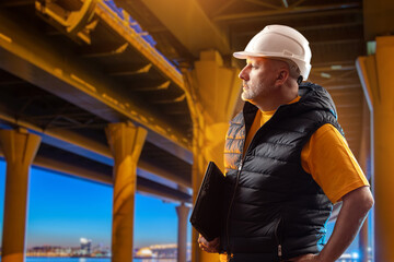 Poster - man builder stands under bridge. construction team foreman. confident builder looks into distance. c