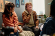 © pressmaster - Group of friends sitting in cozy room, enjoying conversation and laughter while relaxing together, creating a warm and friendly atmosphere