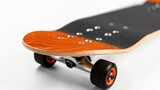 Orange skateboard with black wheels standing on a white background