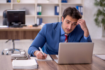 Wall Mural - Young male employee working in the office