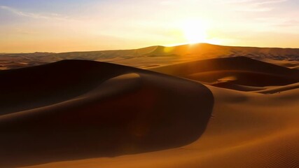 Wall Mural - the vast desert landscape glows in warm, golden light at sunset, casting long shadows over large san