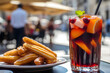 © alfi - Refreshing sangria and churros with chocolate in a lively Madrid plaza on a sunny day