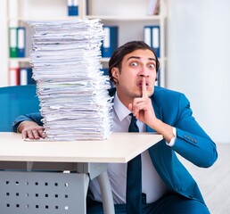 Wall Mural - Young male employee unhappy with excessive work