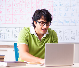 Wall Mural - Young male student chemist in front of periodic table