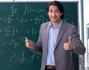 Wall Mural - Young handsome math teacher in classroom