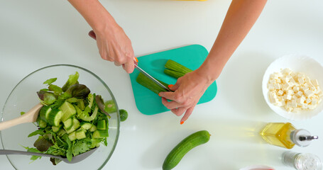 A woman slices cucumbers for a vegetable salad